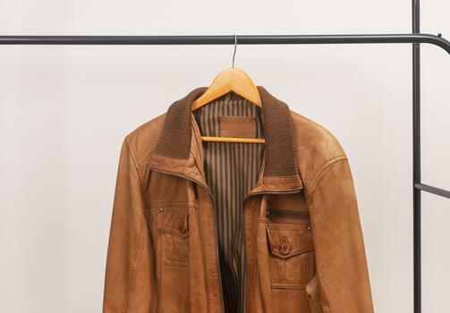 brown leather jacket hanging on rack with zipper outerwear garment placed on wooden hanger menswear wardrobe clothing for autumn spring season photo